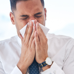 Image of an office worker blowing their nose for article header image